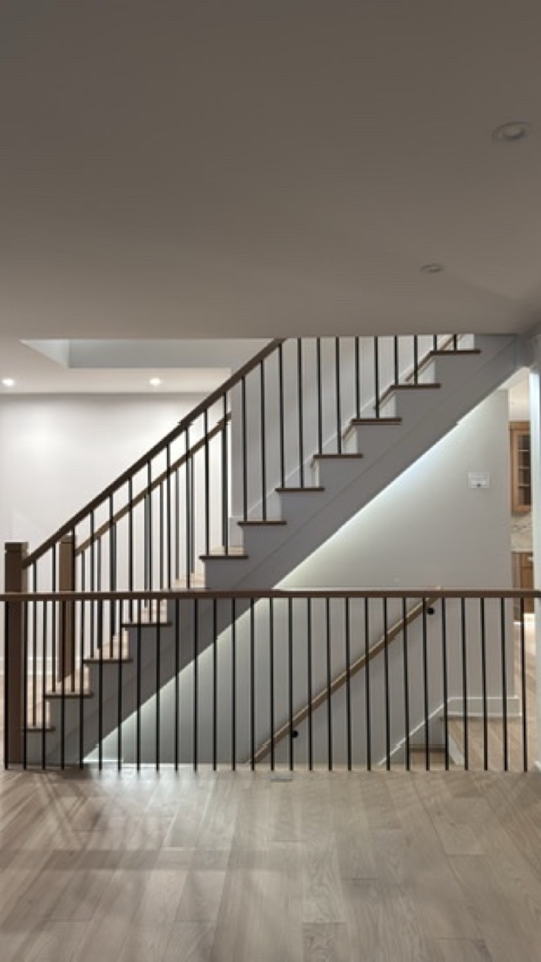 Open staircase with black metal balusters and wood treads at Casa DOS